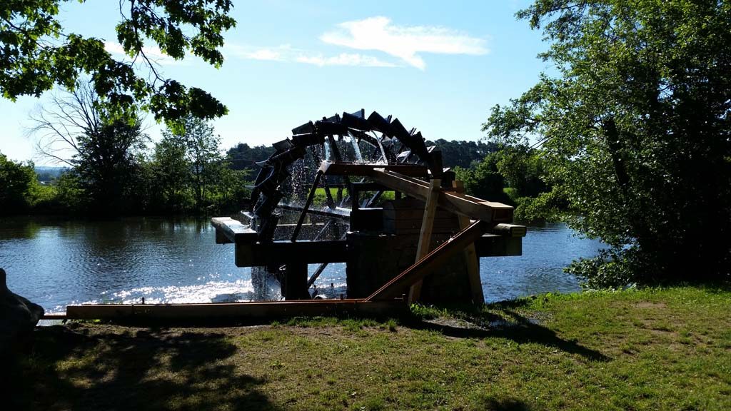 Wasserrad von Hausen Wasserrad an einem ruhigen Gewässer, umgeben von Bäumen und Sträuchern.